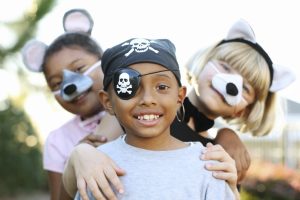 Three children are playing dress-up as different professions: a pirate, a mouse, and a cat.