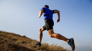 A man trail running up a hill to improve his mental health.