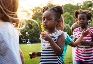 A group of children are blowing bubbles and playing together outside.